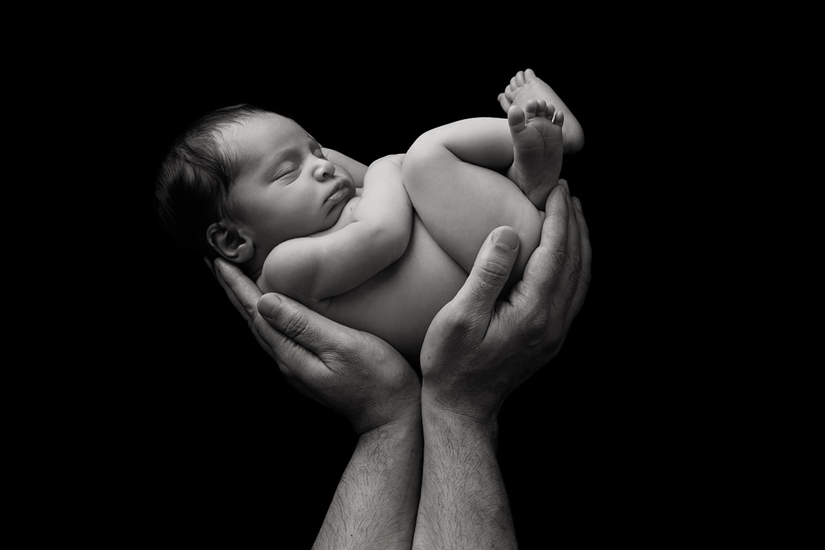 Black and white newborn in daddy's hands portrait