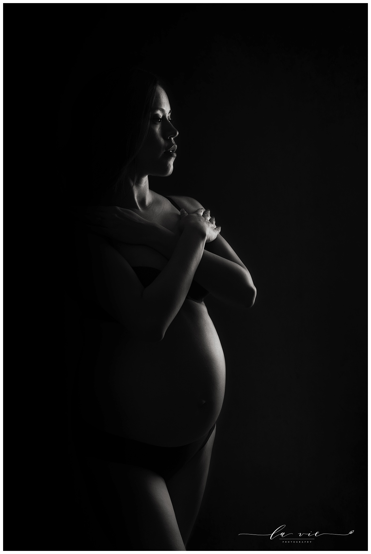 Black and white maternity portrait with dramatic rim lighting