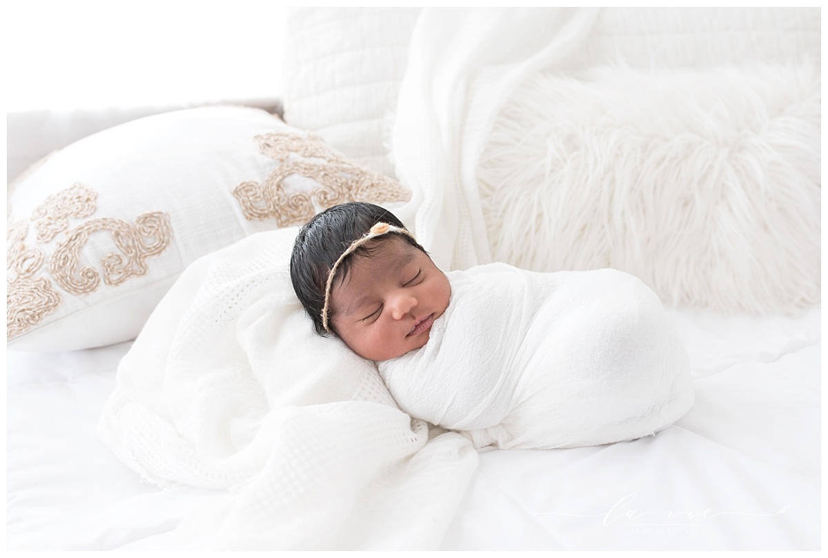 Newborn baby girl swaddled in white with dark hair