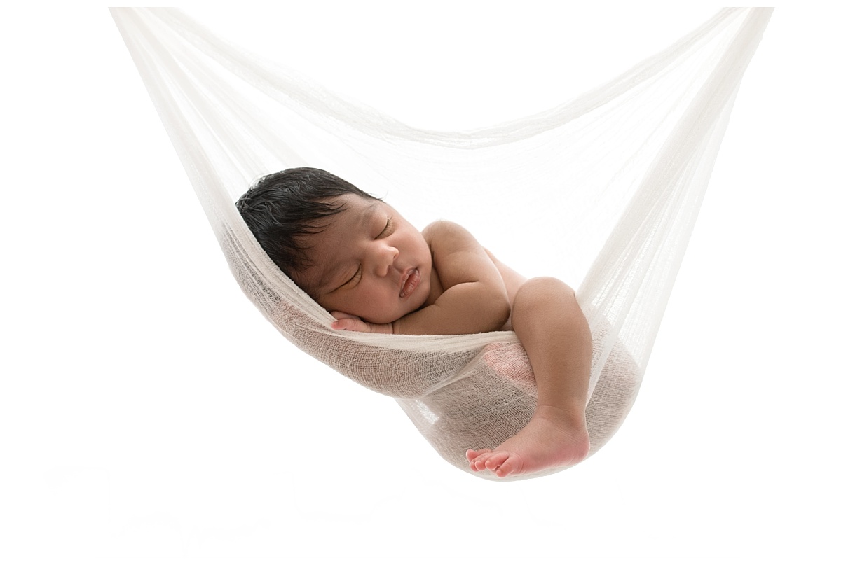 All white backlit portrait of newborn baby in hammock