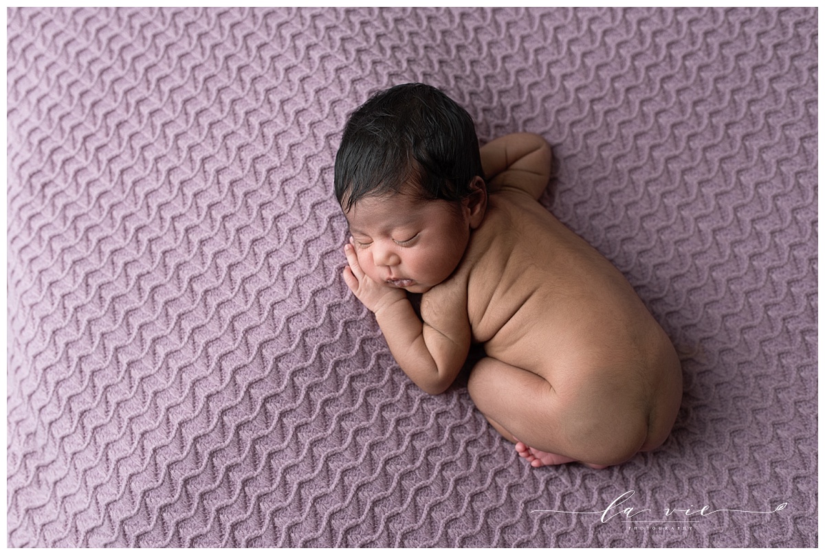 Profile image of newborn baby girl on textured purple blanket