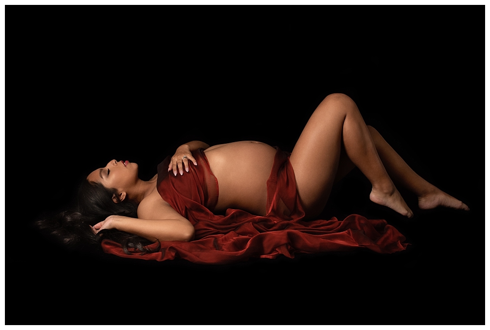 maternity portrait lying on floor draped in red silk